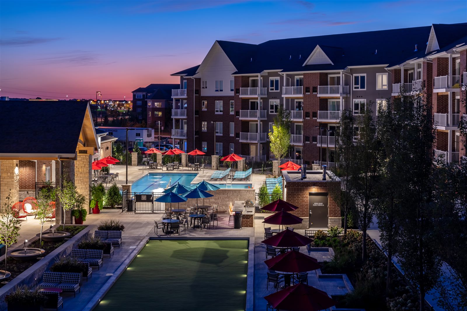 Doran-developed Active Adult community courtyard at dusk, with pool, bocce court and lounge seating