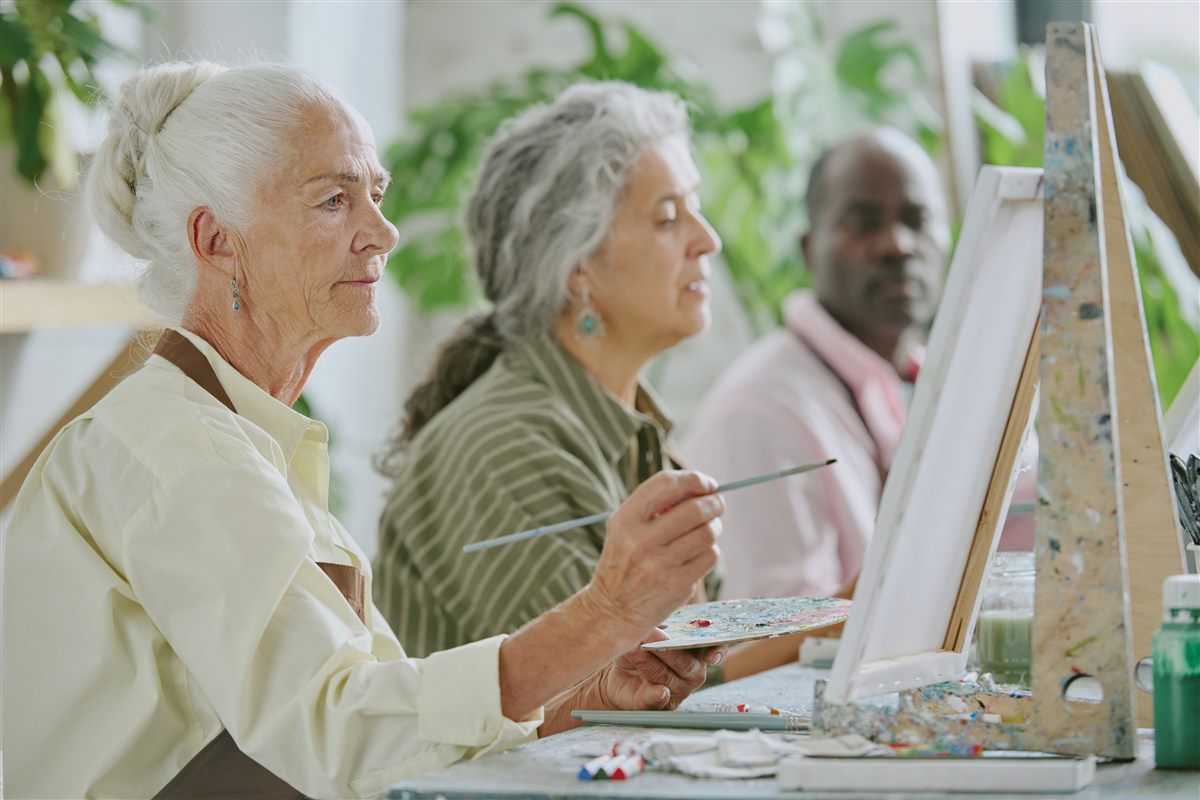Active adult residents in a painting class, engaged in a shared creative activity
